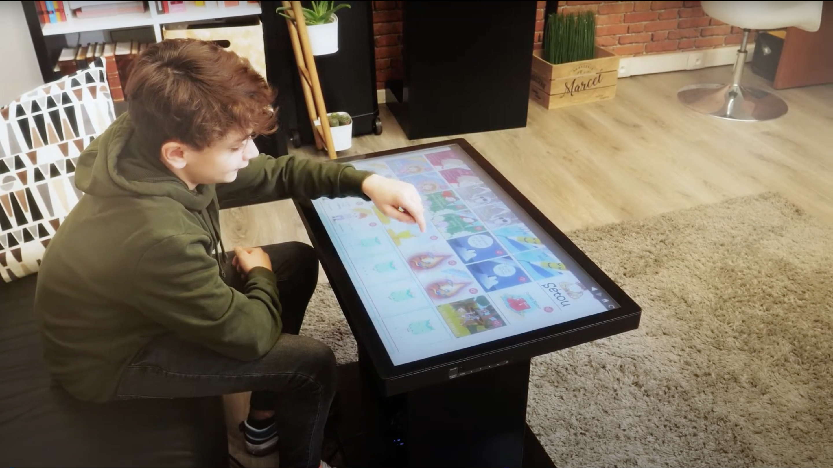 Un enfant sur une table tactile jouant avec de l'application éducative de bibliothèque numérique