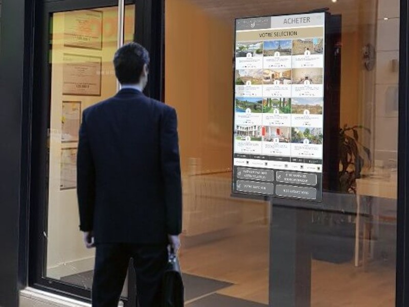 Écran tactile interactif dans la vitrine d'une agence immobilière