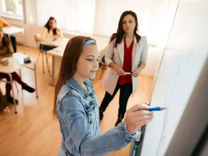 élève qui utilise un tableau blanc interactif dans une salle de classe